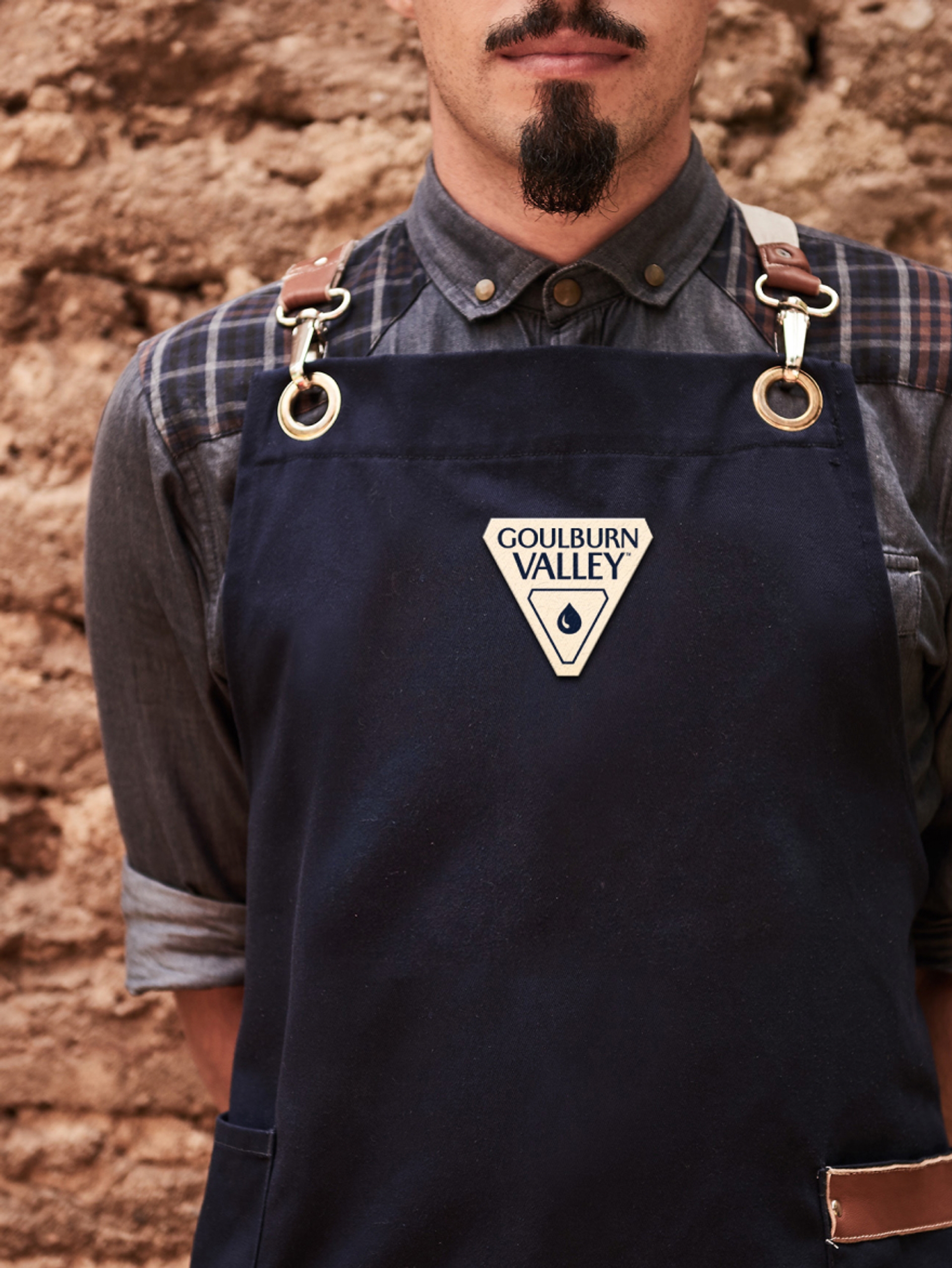 Close up of person wearing a navy apron with Goulburn Valley logo, branding design by Our Revolution