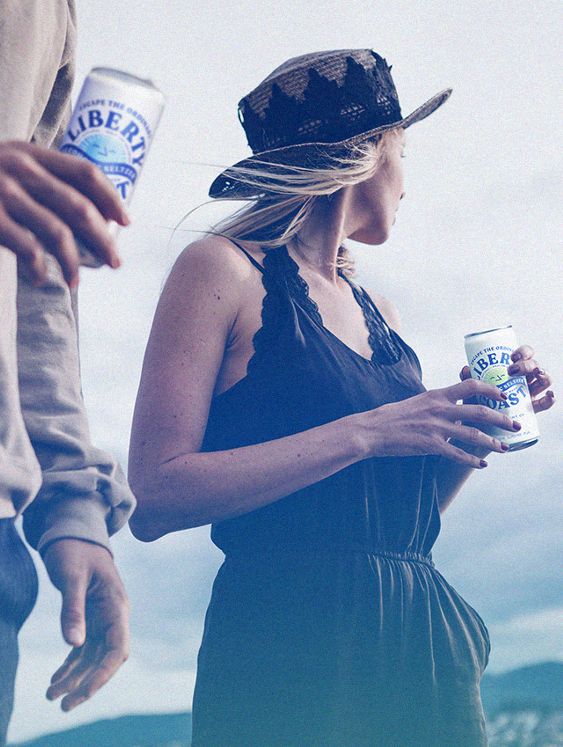Cyan-toned film photography of two figures holding cans of Liberty Coast Alcoholic Seltzer, alcohol packaging design by Sydney design agency Our Revolution